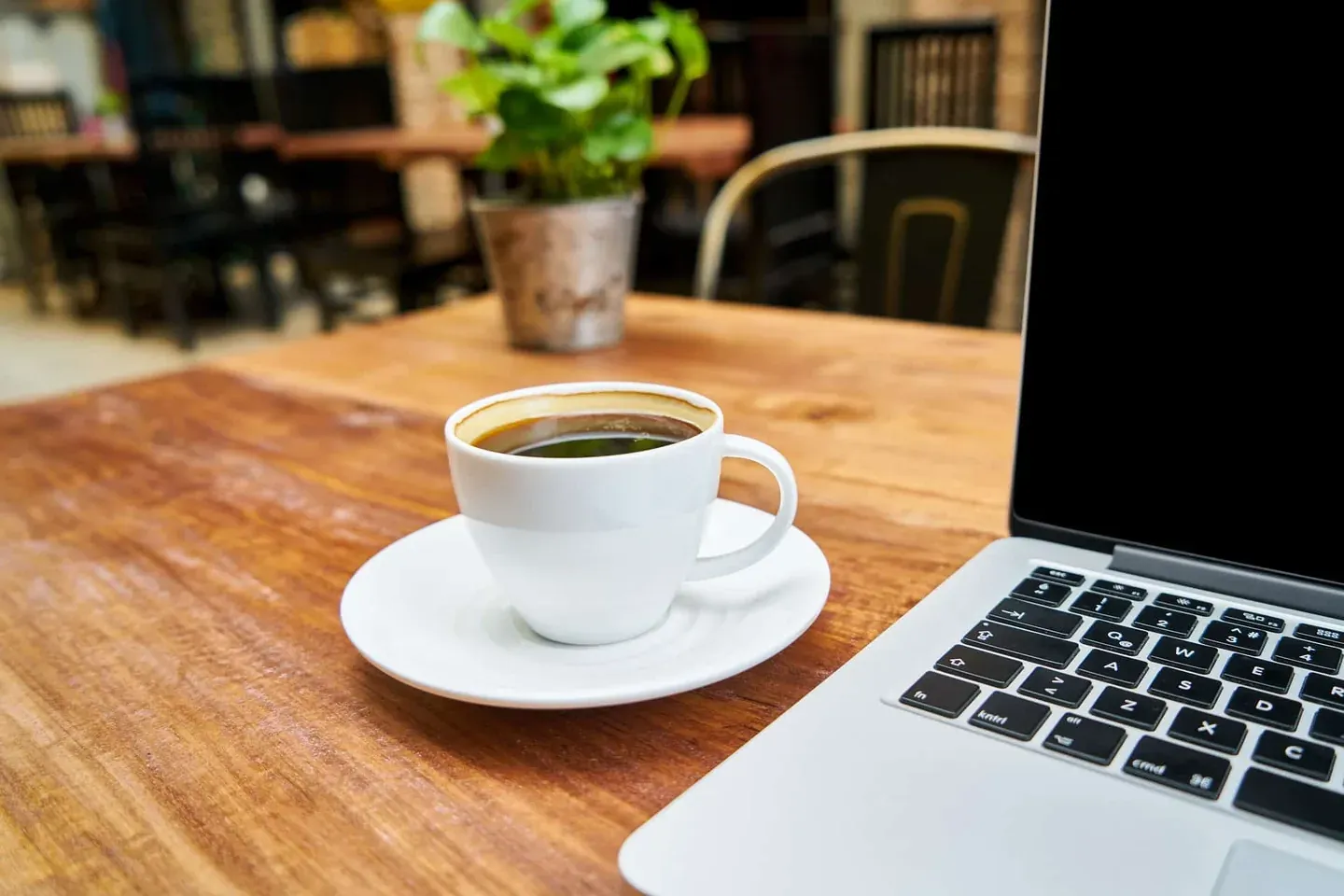 Restaurant owner reviewing technology trends on a laptop with coffee