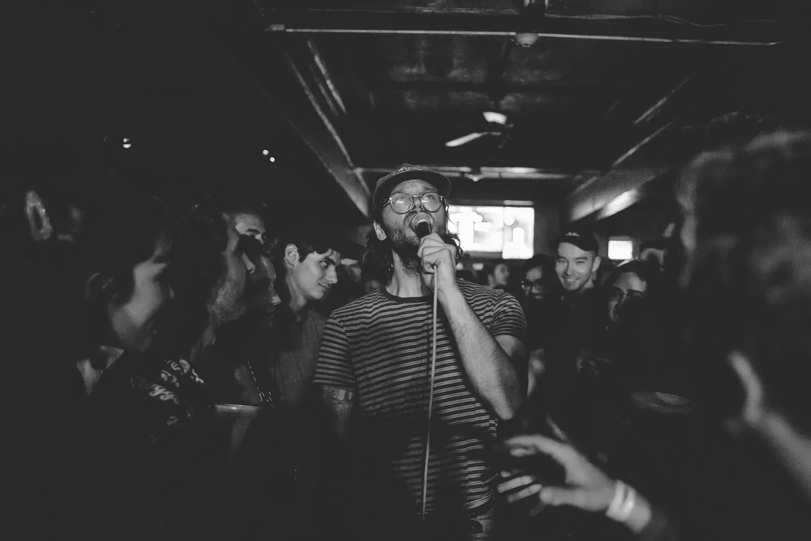 Guest singing karaoke into a microphone in a crowded bar